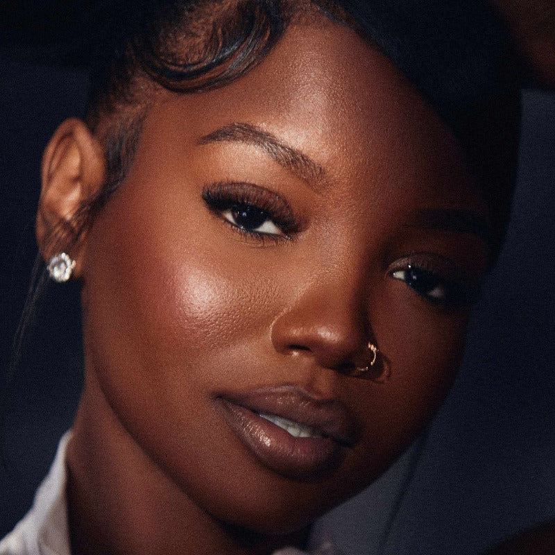poc woman with a nose piercing and soft glam makeup with a beautiful lip combo in an up close portrait photo wearing hayati lashes 777 fluffy lightweight cat eye lashes with an invisible band