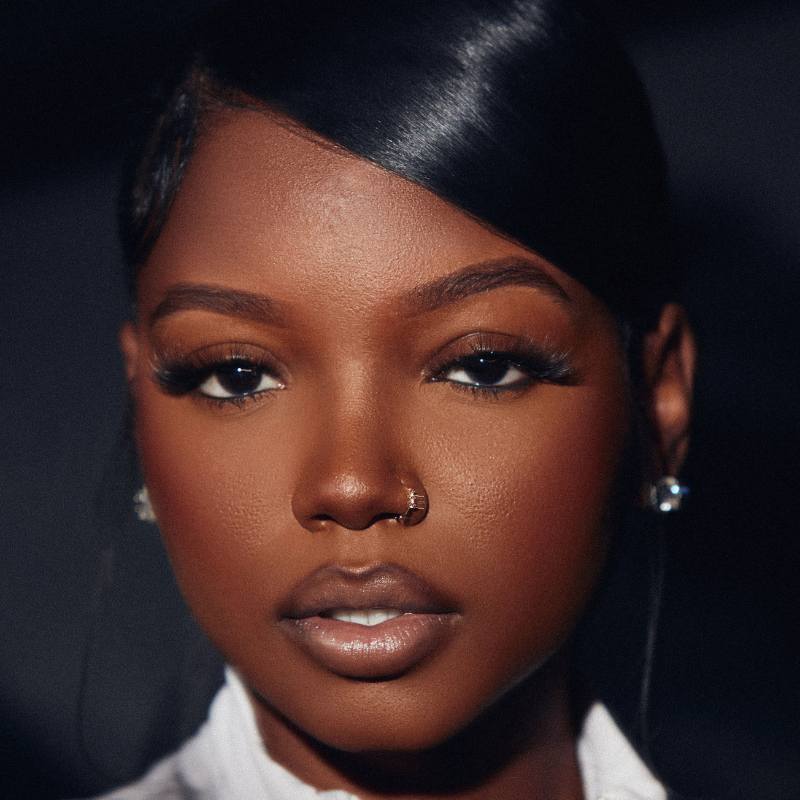 beautiful black woman with a soft glam makeup and a nose ring wearing wispy mega volume strip lashes that are fluffy in a cat eye