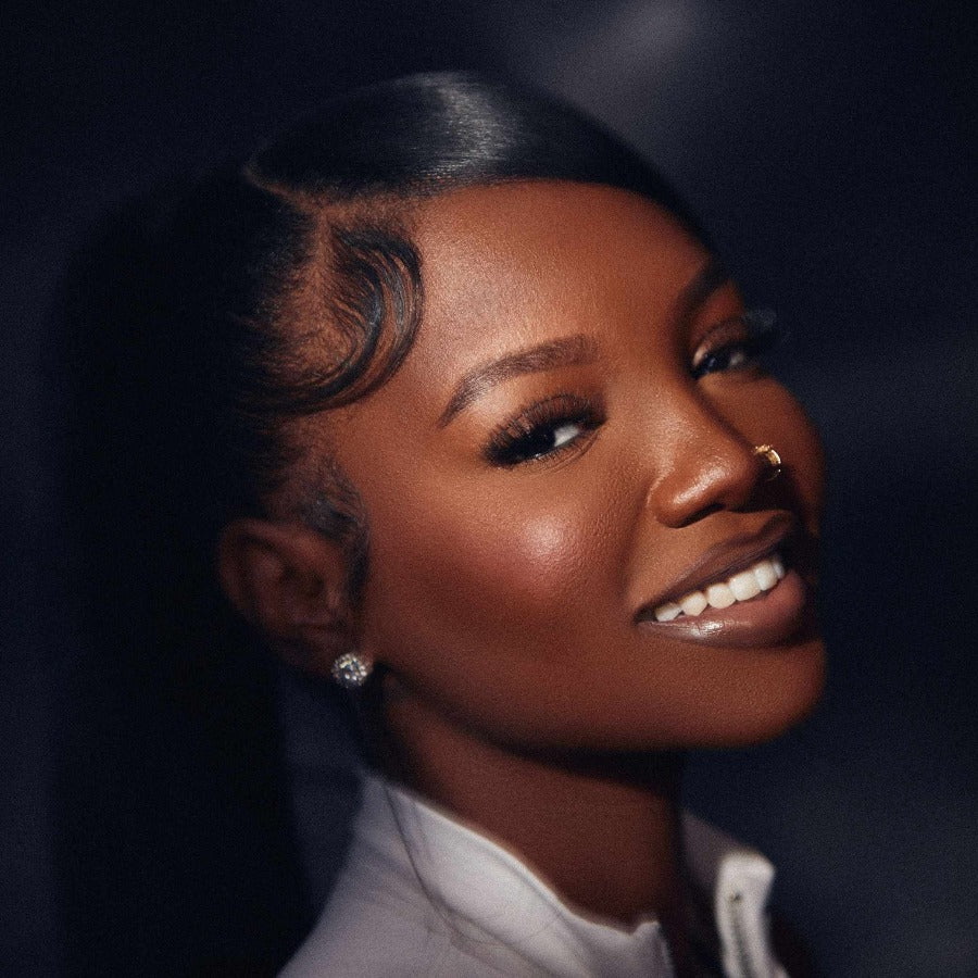 poc woman with a nose piercing and soft glam makeup with a beautiful lip combo in an up close portrait photo wearing hayati lashes 777 fluffy lightweight cat eye lashes with an invisible band